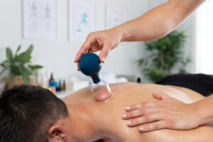 Fisioterapeuta realizando uma sessão de ventosaterapia em um paciente masculino.