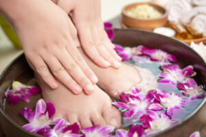 Tratamento de spa e produtos para mãos e pés femininos. Flores de orquídea em uma tigela de cerâmica.