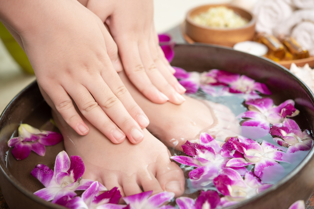 Tratamento de spa e produtos para mãos e pés femininos. Flores de orquídea em uma tigela de cerâmica.