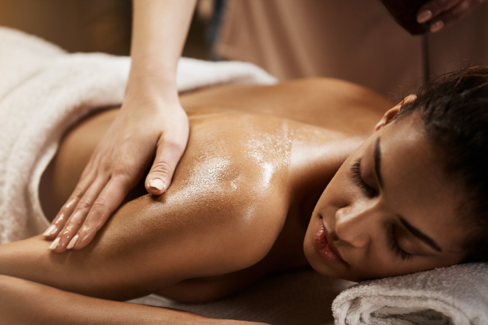 Massagem terapêutica com óleo em mulher deitada, ilustrando os efeitos da ciência aplicada ao toque no relaxamento e na saúde corporal.