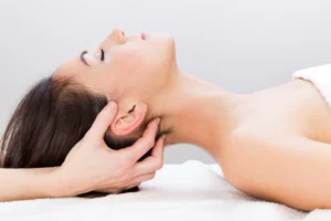 Mulher recebendo massagem no sistema nervoso com foco em relaxamento da cabeça e pescoço para alívio de tensão física e emocional.