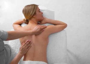 Mulher recebendo massagem tântrica feminina nas costas, com foco em relaxamento, toque consciente e conexão corporal